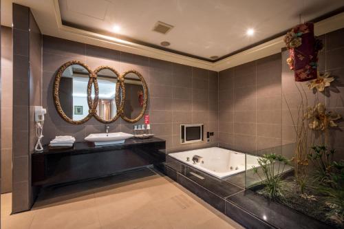 a bathroom with a tub and a sink and mirrors at Belle Song Motel in Shulin