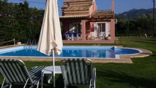 Almiros BeachにあるVilla Filiaの家の前に椅子2脚とパラソル1本付きのプールがあります。