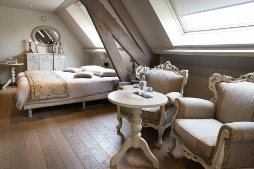 een slaapkamer met een bed en een tafel en stoelen bij Hotel Den Berg in Londerzeel