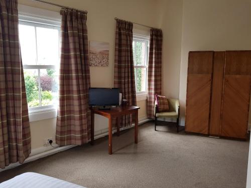 a bedroom with a television and a desk and window at Station Hotel in Hucknall