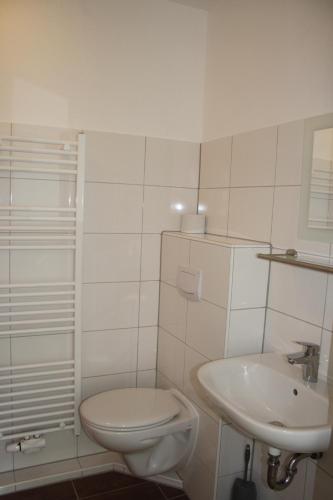 a white bathroom with a toilet and a sink at Muschelsucher in Norden