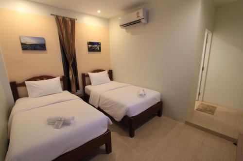 a hotel room with two beds with white sheets at โรงแรมนางรอง in Nang Rong