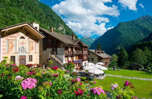 a building with flowers in front of a mountain at Albergo Montagna Di Luce in Alagna Valsesia