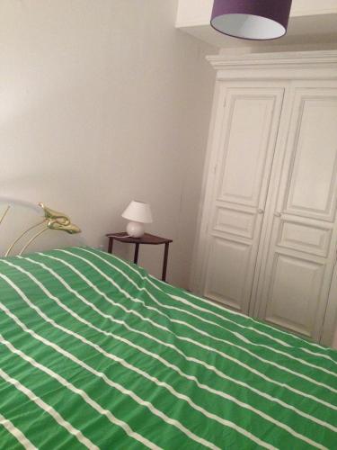 un letto con una coperta a righe verdi e bianche di Rue Du Four a Marcigny