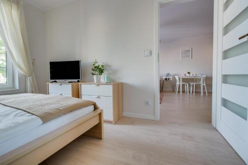 a bedroom with a bed and a television and a dining room at Apartament Crystal in Ustronie Morskie