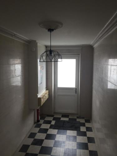a hallway with a door with a window and a checkered floor at L'Oasis Appartement Cosy avec Climatisation, Parking, Vélos , Animaux Bienvenus in Châteauroux