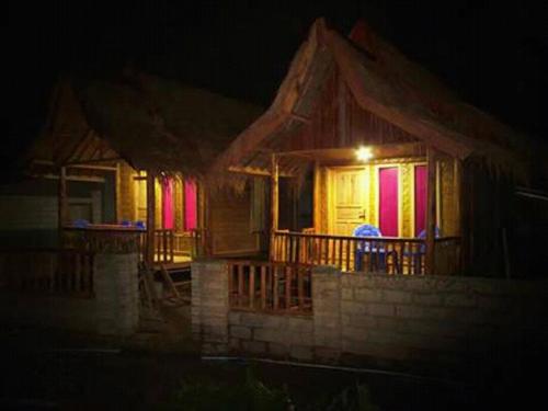 a house with colorful lights on the porch at night at Tereng Wilis bungalows in Tetebatu