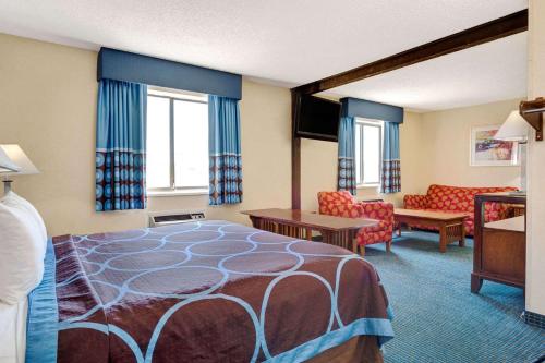 a hotel room with a bed and a living room at Super 8 by Wyndham Hutchinson in Hutchinson