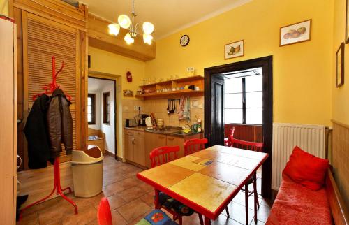a kitchen with a table and red chairs in a room at Hostel Merlin in Český Krumlov