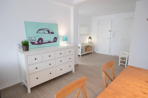 una sala da pranzo con un comò bianco con la foto di una macchina sopra di Apartamento cerca del mar (parking incluido) a Blanes
