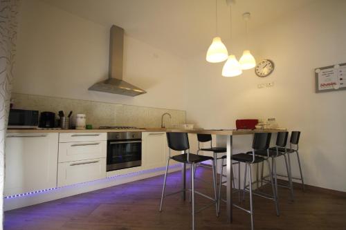 una cocina con armarios blancos y una mesa con taburetes en Villa Savina appartamenti, en Riccione