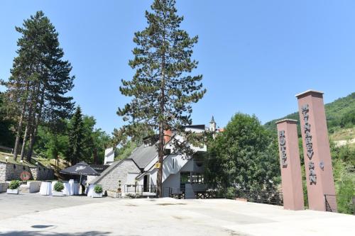 a building with a tree in front of it at Garni Hotel Mlinarev san in Arilje