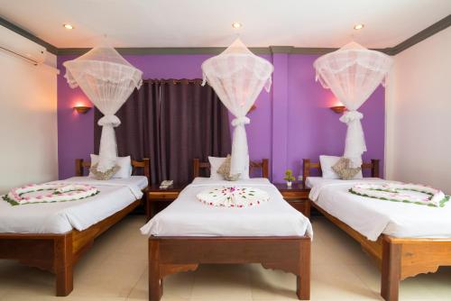 two beds in a room with purple walls at Tan Kang Angkor Hotel in Siem Reap