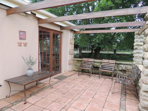 a patio with two chairs and a wooden pergola at Wegkomkans B&B in Fouriesburg