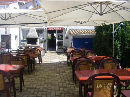 an outdoor patio with tables and chairs and a grill at Auberge Le Chata in Saint-Georges-de-Didonne