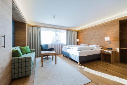 レッヒにあるHotel Garni Panoramaのベッドとソファのあるホテルの部屋