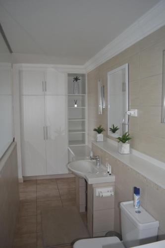 a white bathroom with a sink and a toilet at Beach Retreat Guesthouse in Amanzimtoti
