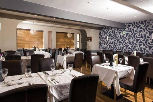 a dining room with white tables and black chairs at The Ship Hotel in Aberdaron