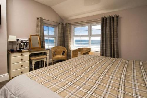 a bedroom with a bed and a desk and windows at The Ship Hotel in Aberdaron