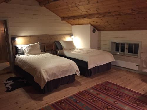 1 Schlafzimmer mit 2 Betten in einem Zimmer mit einem Teppich in der Unterkunft Marjas stuga in Norråker