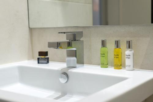 a bathroom sink with two bottles of soap and a faucet at Cuatro Caminos Rooms in Torrelavega