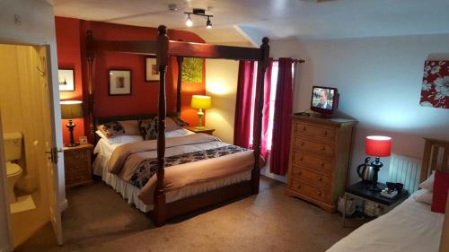 a bedroom with a four poster bed and red walls at Lynebank House Hotel, Bed & Breakfast in Carlisle