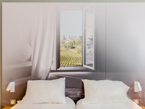 a bedroom with two beds and a window at B&B HOTEL Bordeaux Mérignac Hôtel de Ville in Mérignac