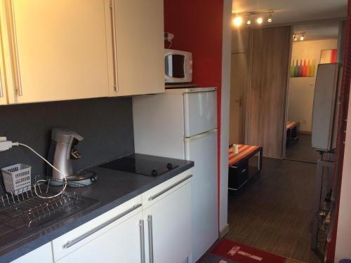 une cuisine avec des armoires blanches et un réfrigérateur blanc dans l'établissement Appartement vue sur lac, à Gérardmer