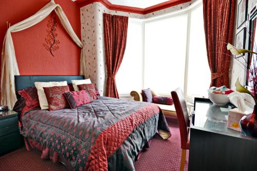 a bedroom with a bed with red walls and a window at The Astor Hotel in Blackpool