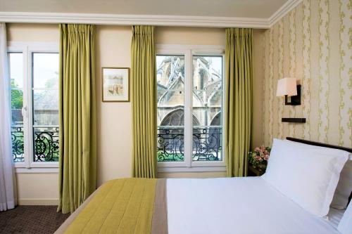 a bedroom with a large window and a large bed at Hôtel Henri IV Rive Gauche in Paris