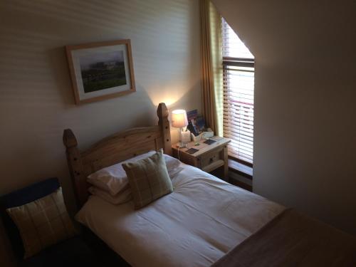 a bedroom with a bed and a lamp and a window at Kylelachin in Dingwall