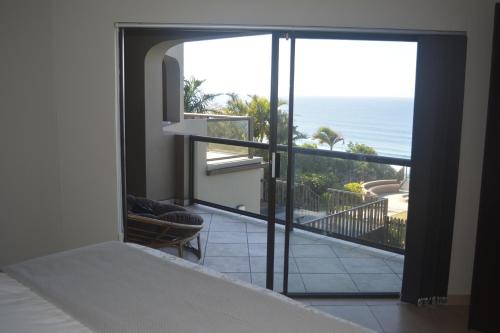 a bedroom with a balcony with a view of the ocean at Beach Retreat Guesthouse in Amanzimtoti