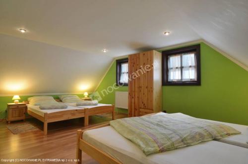 sypialnia z 2 łóżkami i zieloną ścianą w obiekcie Drevenica u Petra w Tierchowej