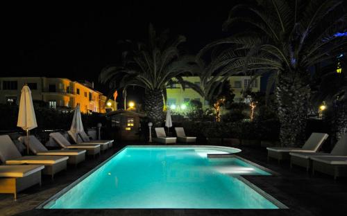 a swimming pool at night with lounge chairs and palm trees at Hotel Europa in Lido di Camaiore