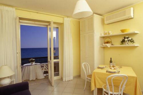 Residence Sole Mare Alaxi Hotels في ألاسيو: غرفة طعام مع طاولة وإطلالة على المحيط