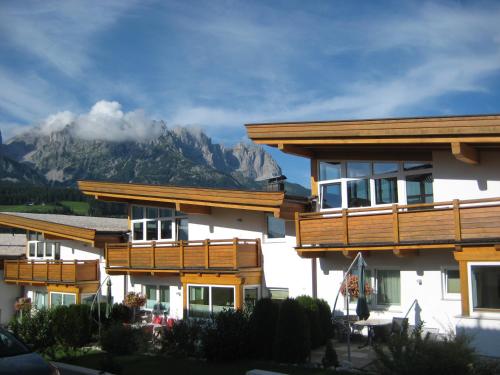 a building with wooden balconies with mountains in the background at Alpenchalets Wilder Kaiser in Ellmau