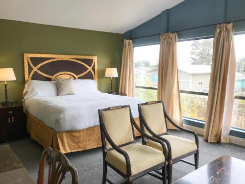a bedroom with a large bed and two chairs at Bodega Bay Inn in Bodega Bay