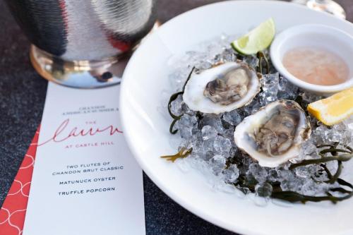 a plate of oysters on ice with a menu at Castle Hill Inn in Newport