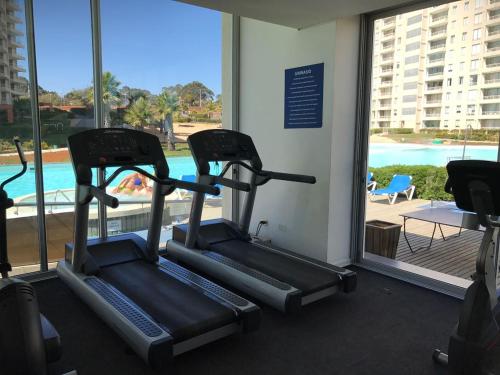 2 bicicletas estáticas en un gimnasio con vistas a la piscina en Departamento Laguna Vista Algarrobo, en Algarrobo