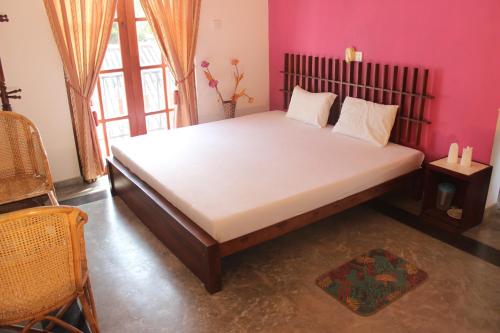 um quarto com uma cama grande num quarto cor-de-rosa em Sanras Hotel and Restaurant em Galle