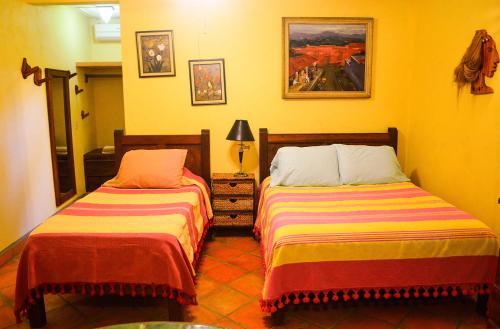 two beds in a room with yellow walls at Hotel Casamar Suites in Puerto Escondido