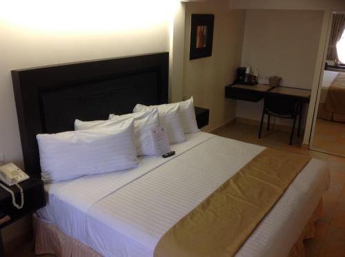 a hotel room with a large bed with white pillows at Best Western Hotel Plaza Matamoros in Matamoros