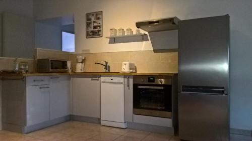 eine Küche mit weißen Schränken und einem Kühlschrank aus Edelstahl in der Unterkunft Le Grenier Maufoux in Beaune