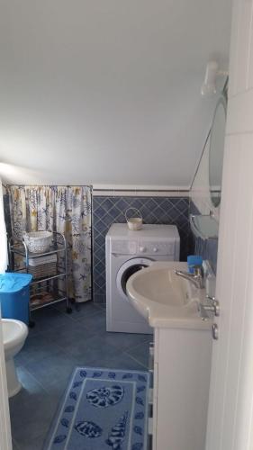 a bathroom with a washing machine and a sink at Mansarda Camelie via dei Normanni, 45 in Campofelice di Roccella