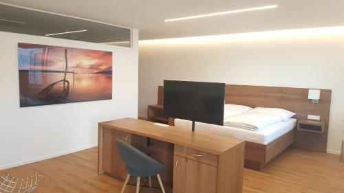 a bedroom with a desk and a bed with a monitor at Seesuiten Mörbisch in Mörbisch am See