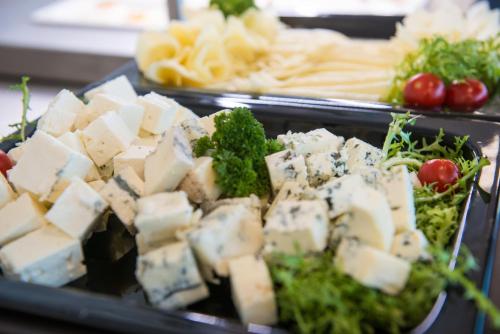 a tray of food with cheese and vegetables on a table at Grid Hotel in Brno