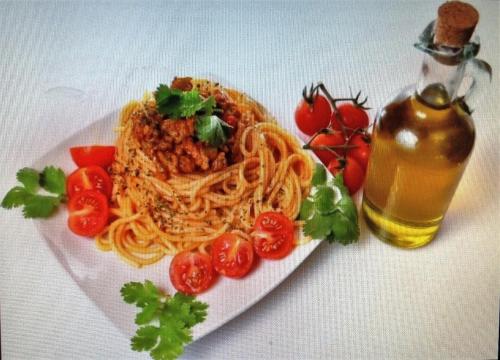 a plate of spaghetti and tomatoes and a bottle of oil at Hotel Caribe in Santa Cruz de Barahona