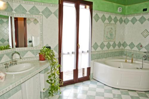 bagno con 2 lavandini, vasca e specchio di Casa vacanze Sandalia a Bosa