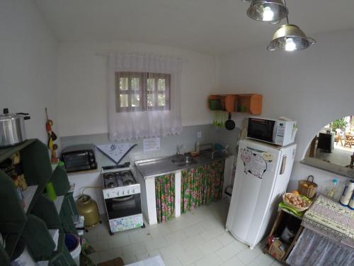 a kitchen with a refrigerator and a stove top oven at Pousada Tikuna in Itacaré