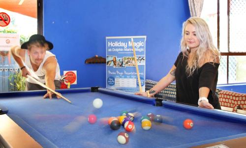 two women playing a game of pool with cues at Aussitel Backpackers in Coffs Harbour
